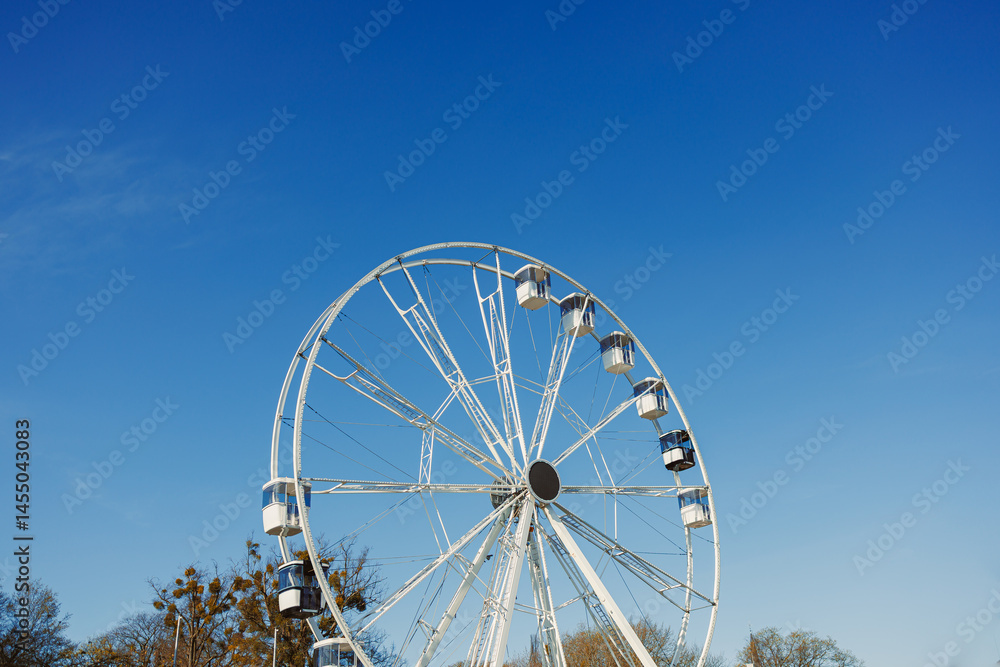 A large Ferris wheel against a blue sky. Cabins on the Ferris wheel.