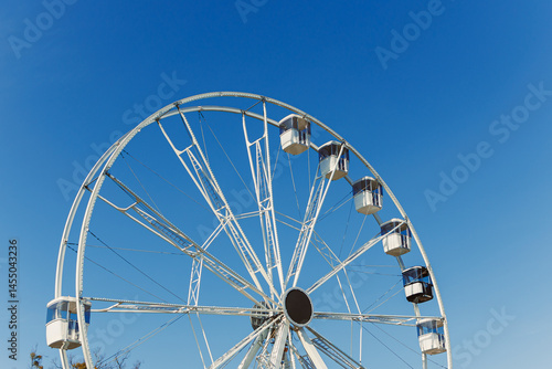 Obraz na płótnie A large Ferris wheel against a blue sky. Cabins on the Ferris wheel. w salonie