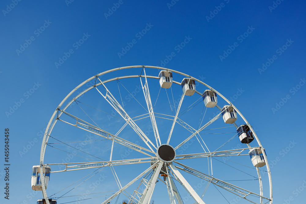 A large Ferris wheel against a blue sky. Cabins on the Ferris wheel.