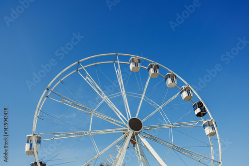 Obraz na płótnie A large Ferris wheel against a blue sky. Cabins on the Ferris wheel. w salonie