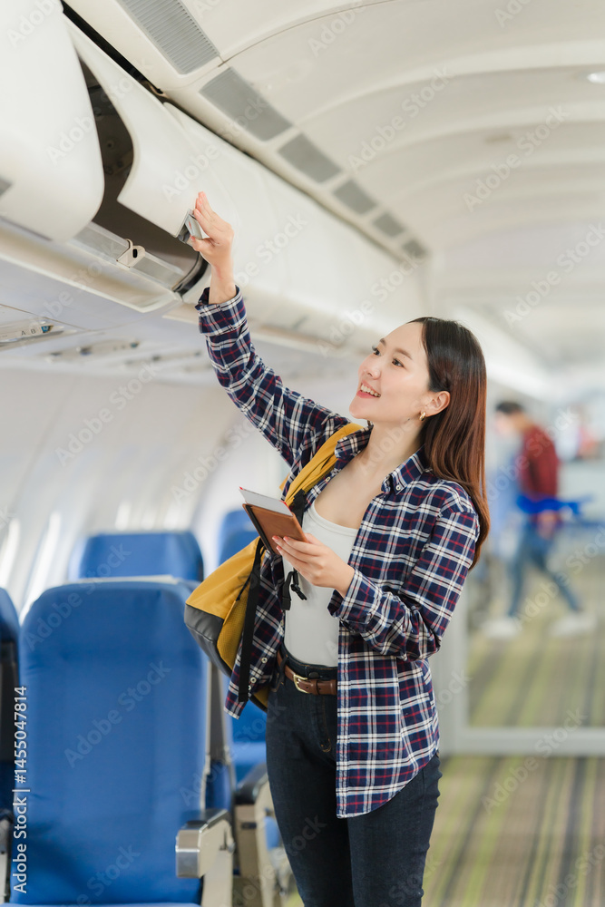 Woman Placing Luggage in Airplane Overhead Compartment