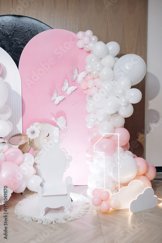 Pink photo zone for children's birthday with helium white balloons. Bright celebration of children's birthday with blue balloons.