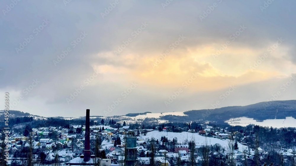 Obraz premium A Serene Winter Landscape Featuring a Smokestack, SnowCovered Hills, and a Tranquil Atmosphere