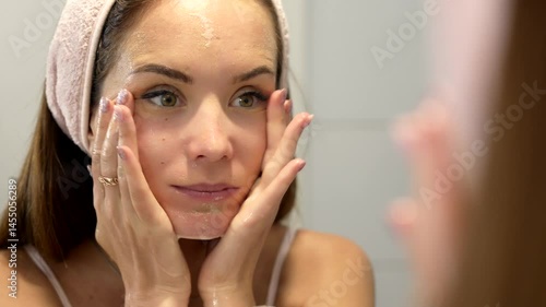 Close-up of a woman washing her face after applying facial cleanser, rinsing skin with water as part of her morning skincare ritual