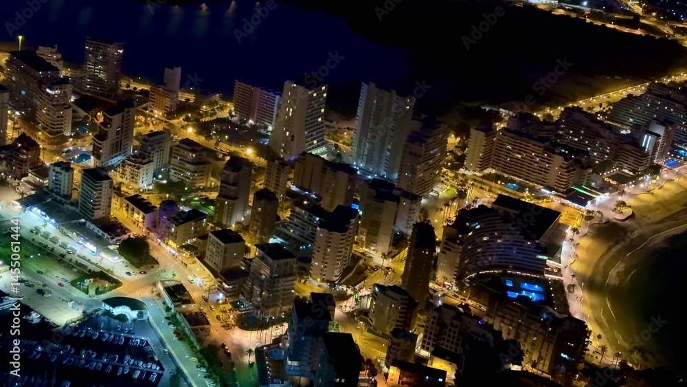 Obraz premium Experience the Stunning Aerial Night View of a Beautiful Coastal City, Filled with Lights and Life