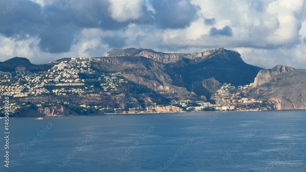 A breathtaking scenic coastal view featuring majestic mountains and fluffy clouds in the sky A breathtaking scenic coastal view featuring majestic mountains and fluffy clouds in the sky