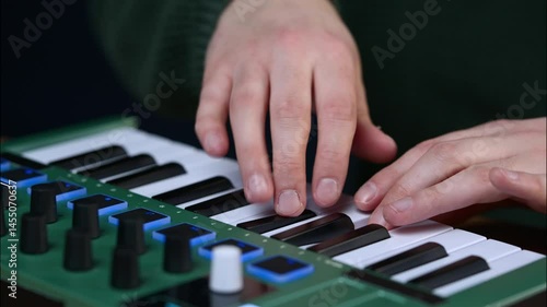 Close-up of male hands playing a mint green dual-action MIDI keyboard.
