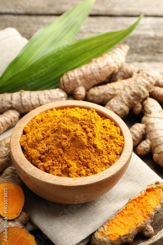 Fototapeta Naklejka Na Ścianę i Meble -  Turmeric powder in bowl, roots and leaves on table, closeup