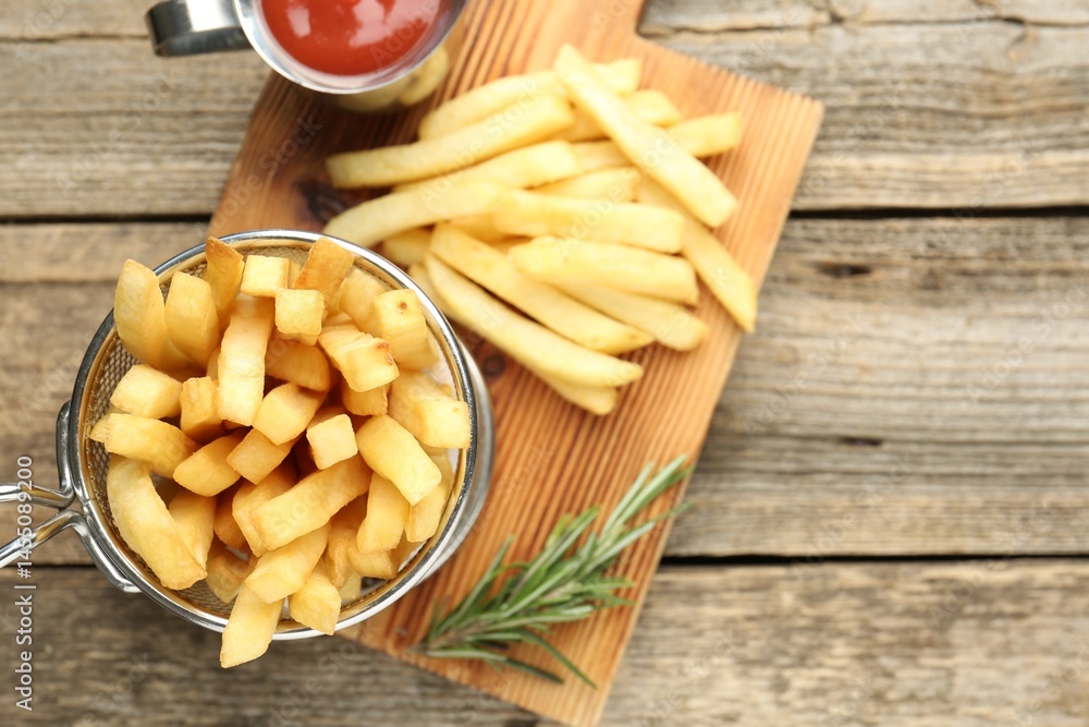 Tasty french fries served with ketchup and rosemary on wooden table, top view. Space for text Tasty french fries served with ketchup and rosemary on wooden table, top view. Space for text