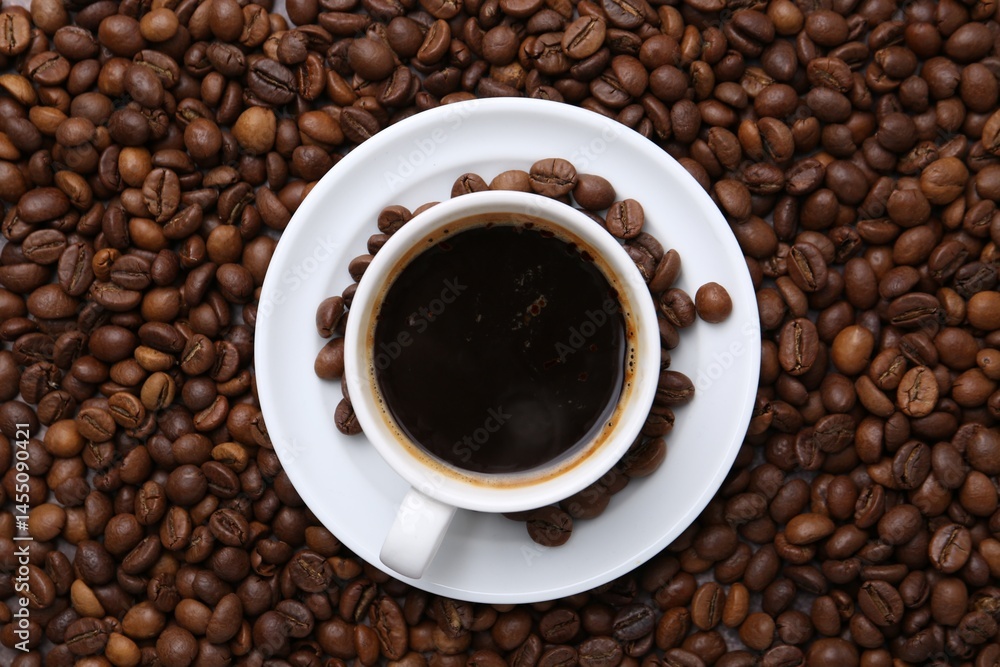 Fototapeta premium Aromatic coffee in cup, saucer and beans, top view