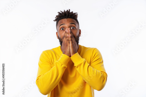 Obraz na płótnie A man in a yellow sweater looks surprised, covering his face with his hands. w salonie