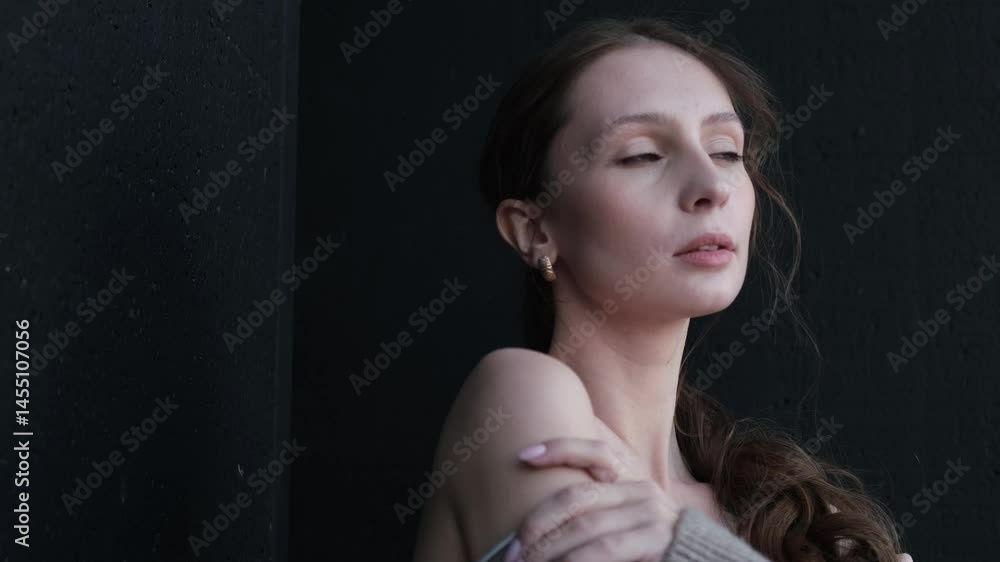 Portrait of a beautiful young girl with bare shoulders on a dark studio ...