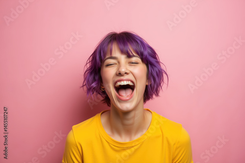 Obraz na płótnie A woman with vibrant purple hair is laughing heartily, wearing a yellow shirt against a pink background. w salonie