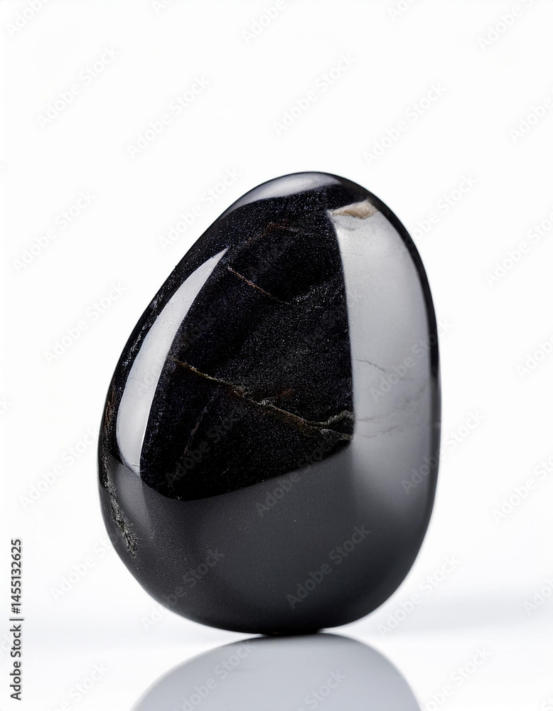 Polished black obsidian stone on a white surface, showcasing its smooth texture and reflective surface. Polished black obsidian stone on a white surface, showcasing its smooth texture and reflective surface.