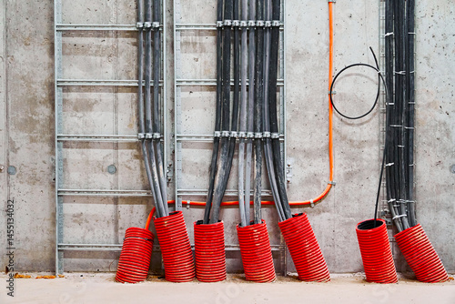 Organized Installation of Multiple Electrical Cables and Conduits Secured to a Concrete Wall with Metal Supports.