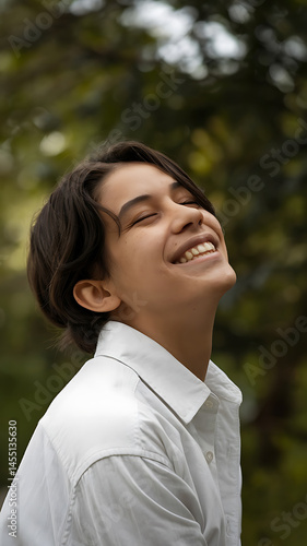 Happy, light-skinned person, likely a teenager, with dark hair, smiling broadly, outdoors.