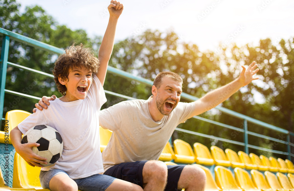 Obraz premium Goal. Emotional man and little boy cheering their favorite team, little boy holding soccer ball