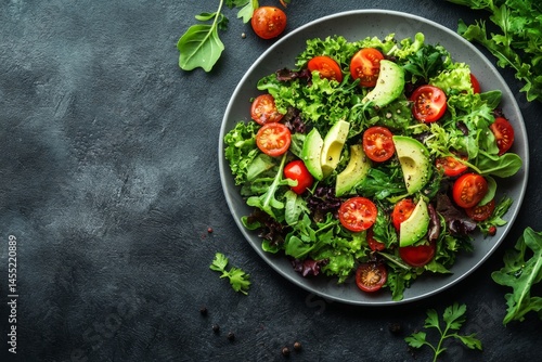 Top view of healthy green salad with tomatoes cucumbers and dressing in a bowl