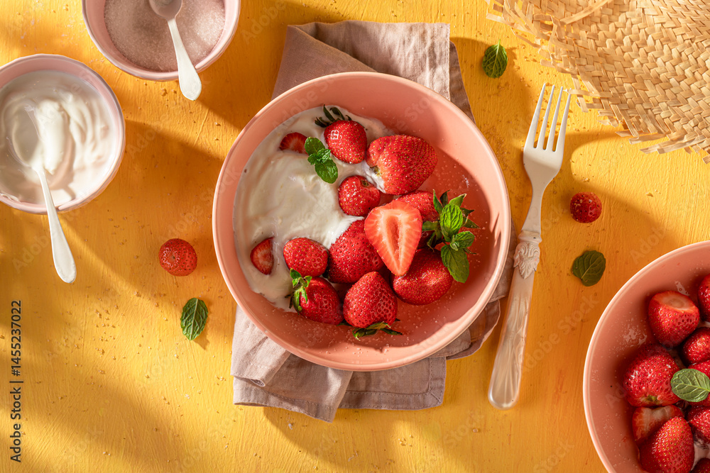 Fresh and sweet strawberries on yellow sunny table.