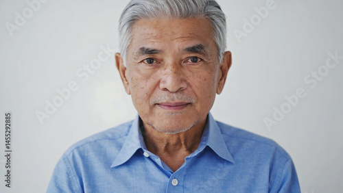Close-up portrait captures an elderly Asian man with gray hair, gazing forward peacefully