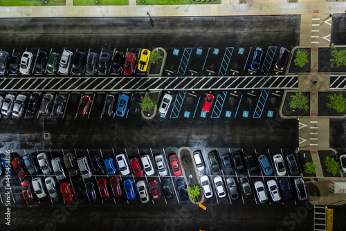 Cars parked in a crowded urban parking lot, under a clear blue sky.