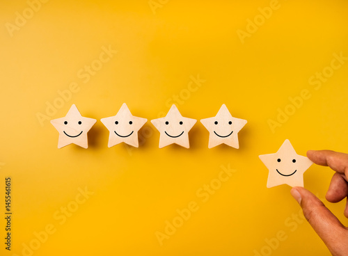 Принти на полотні Happy smile face emoticon on stars, on yellow background and hand holding one star for more rating satisfaction