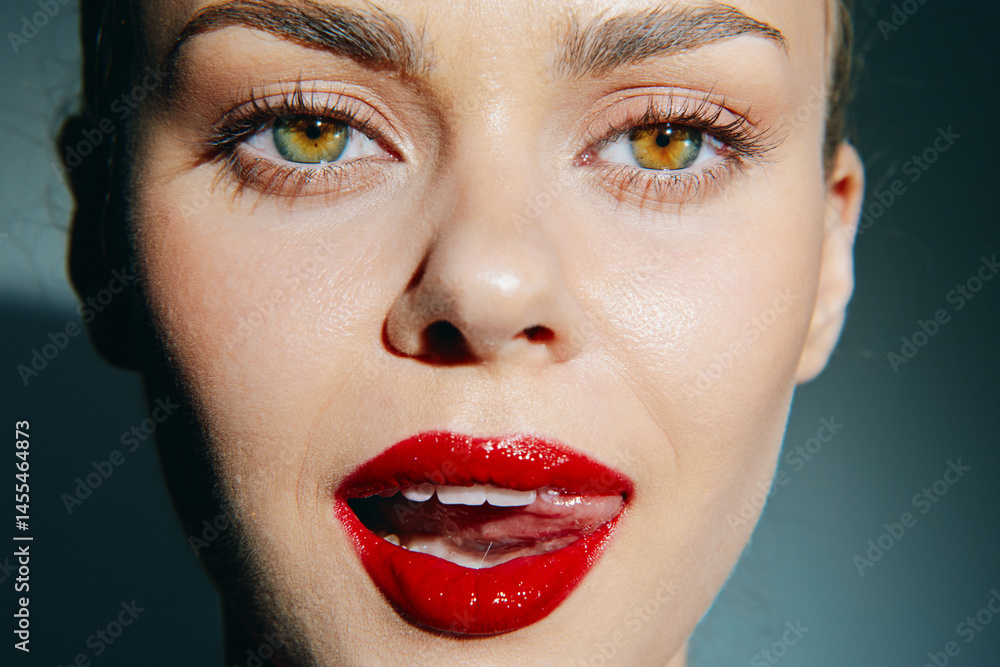Close-up portrait of a female model with striking green eyes and bold red lipstick, showcasing beauty and confidence with a soft, blurred background.