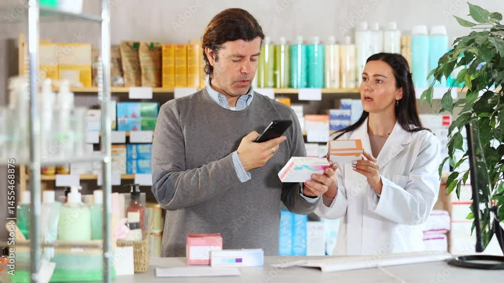 Attentive middle-aged male client controlling QR code of medicament and apothecary giving offer in drugstore Attentive middle-aged male client controlling QR code of medicament and apothecary giving offer in drugstore