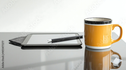 A tablet and a pencil are on a table next to a yellow mug
