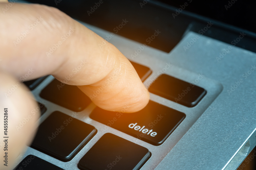 Finger of the computer user, he presses the delete button on the computer keyboard