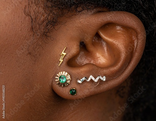 Closeup of Woman's Ear with Multiple Gold and Emerald Piercings