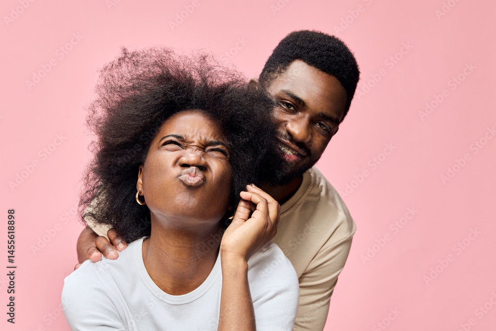 Obraz premium Happy couple with natural hair expressing joy against a pink background, showcasing love and fun in a stylish and playful moment