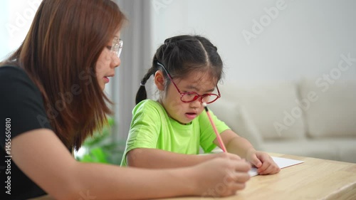 Caring mother helping her child with homework while sitting at the table, focused on education and connection in a cozy home environment