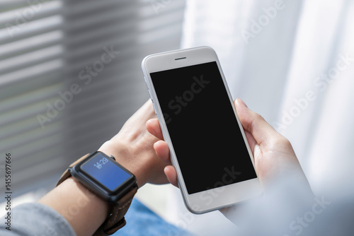 Hand holding smartphone with a blank screen on table, for putting advertising to promote.
