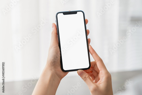 Hand holding smartphone with a blank screen on table, for putting advertising to promote.
