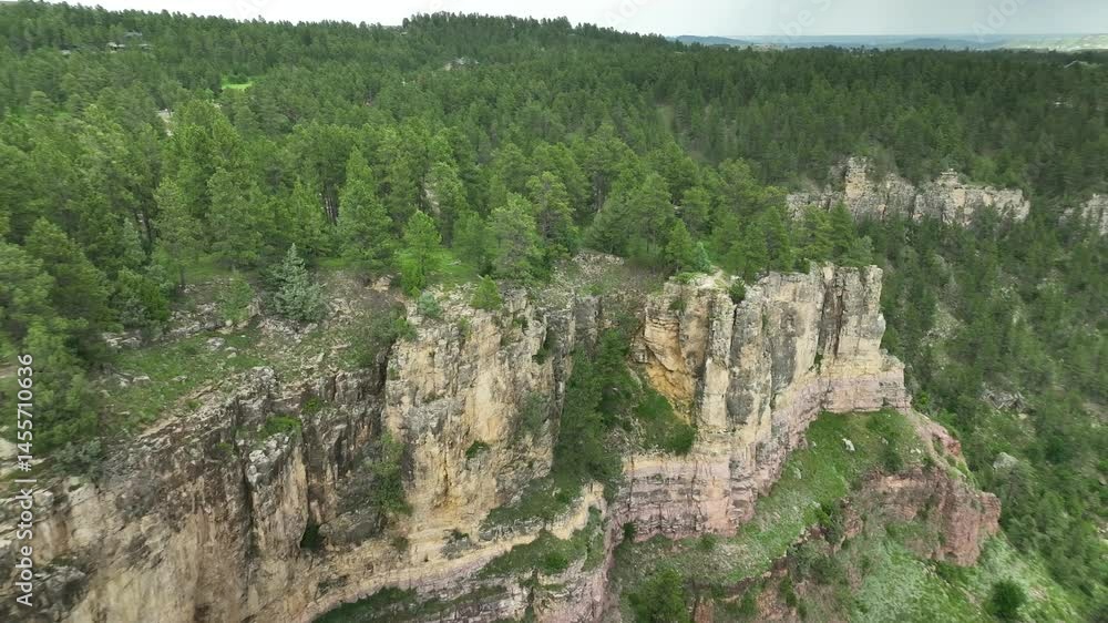 Drone shot orbiting around a cliff edge in a forested area Drone shot orbiting around a cliff edge in a forested area