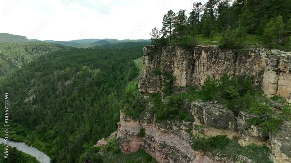 An orbiting and panning drone shot of a cliff in the forest An orbiting and panning drone shot of a cliff in the forest