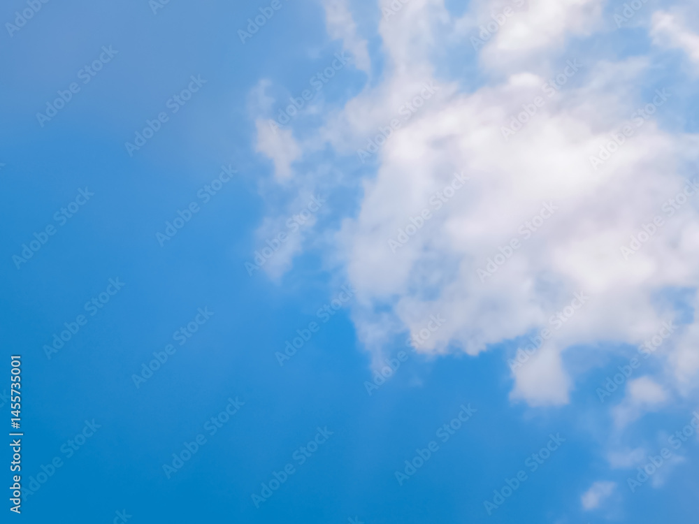 Obraz premium Clear Blue Sky with Soft White Clouds on a Sunny Day. Bright blue sky with gentle white clouds scattered across a sunny backdrop