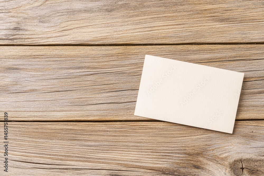 Blank card on weathered wooden planks. A light beige rectangular card lies on a backdrop of horizontal wooden planks. The wood grain is prominent, showing variations in color and texture. Blank card on weathered wooden planks. A light beige rectangular card lies on a backdrop of horizontal wooden planks. The wood grain is prominent, showing variations in color and texture.