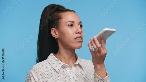 Woman using voice command or recording audio on phone on blue