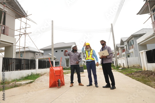 Two black foremen and a multi-ethnic Caucasian construction manager attend a construction inspection meeting and consult on construction inspections on a construction project.