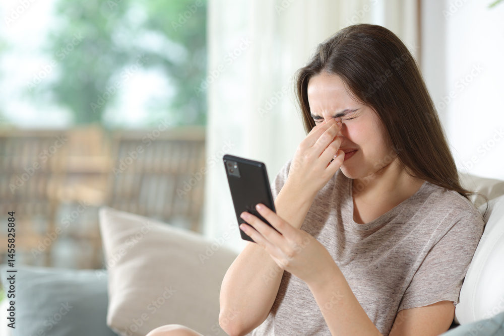 Woman using phone suffering eye strain at home Woman using phone suffering eye strain at home