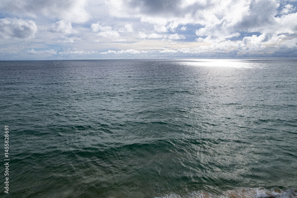 Fototapeta premium Aerial view of a blue sea surface water texture background and sun reflections Aerial flying drone view Waves water surface texture on sunny tropical ocean in Phuket island Thailand