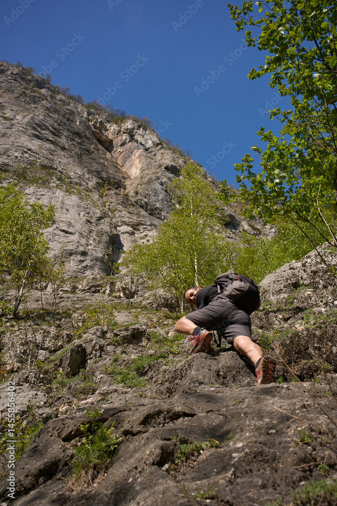 Obraz premium Man climbing rocky slope