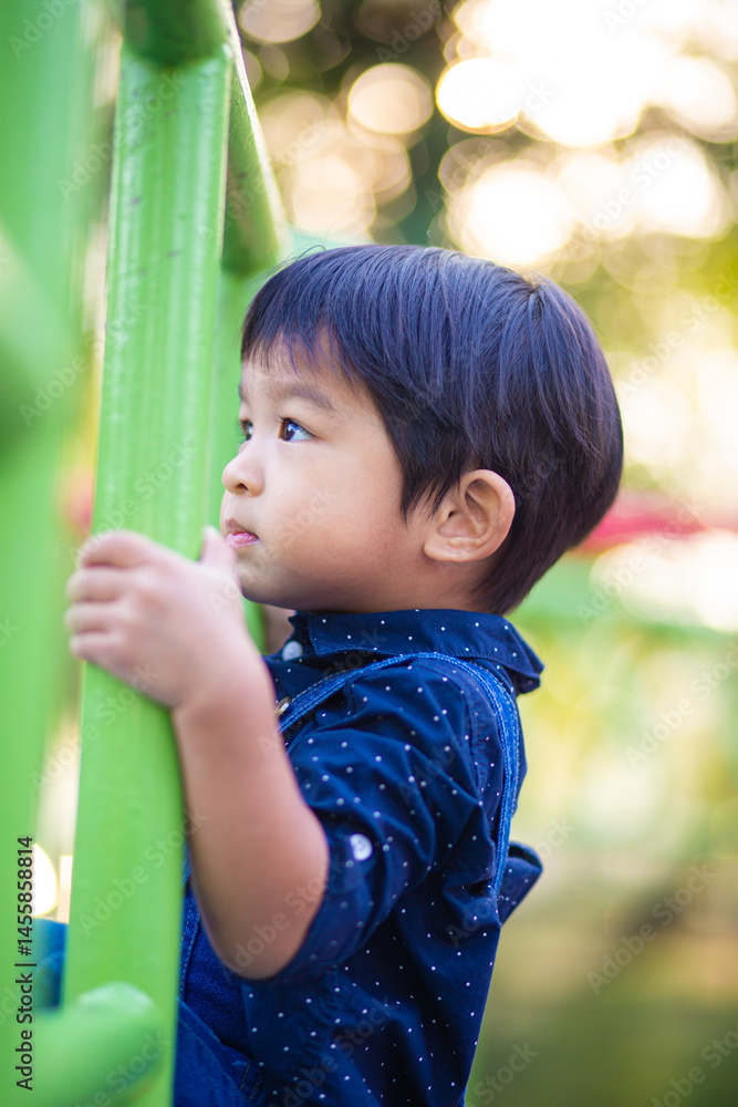 Adorable little asian 2 - 3 year boy climbing practice in playground outdoor