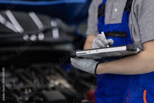 Close-up hand of Professional mechanic holding the tablet for maintenance checklist vehicle, Software for manager check to repair
