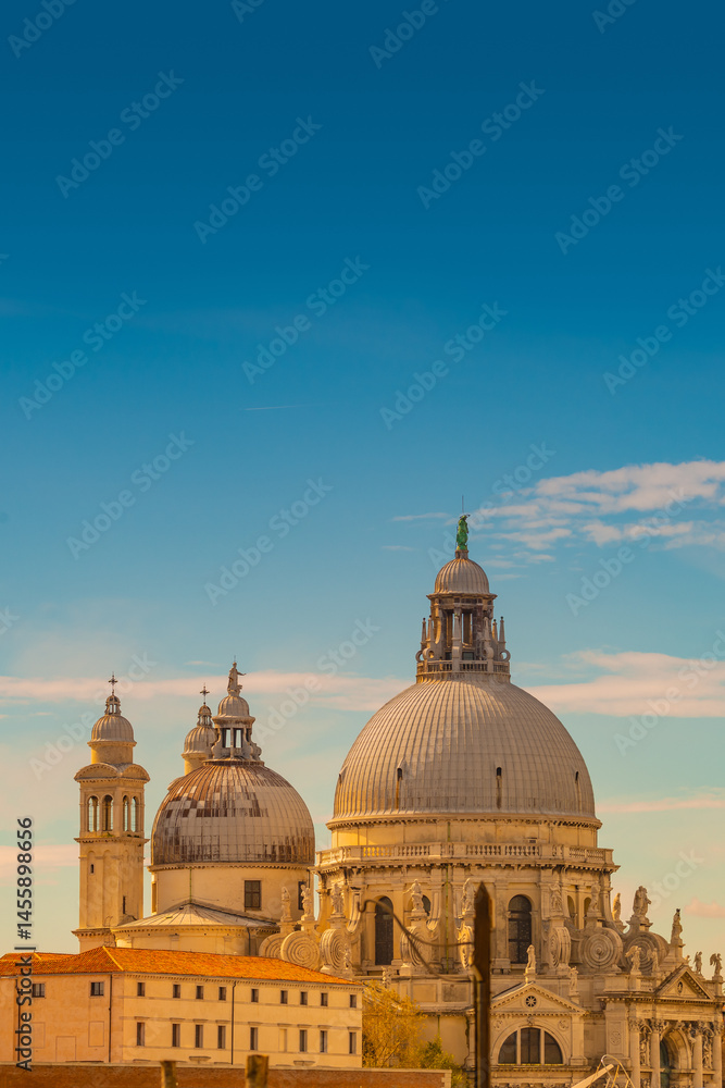 Fototapeta premium Cover page with Basilica di Santa Maria della Salute at beautiful calm sunset and blue sky with copy space Venice, Italy. Concept of religion and historical heritage.