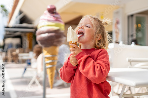 Obraz na plátně A happy young child with blond hair and freckles, dressed in a red sweatshirt, e