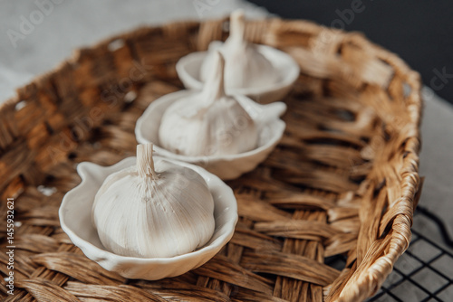 Fresh garlic cloves displayed in small dishes on a woven basket