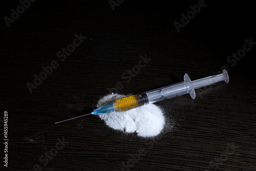 syringe on a handful of white powder resembling a narcotic. The concept of stopping drug addiction